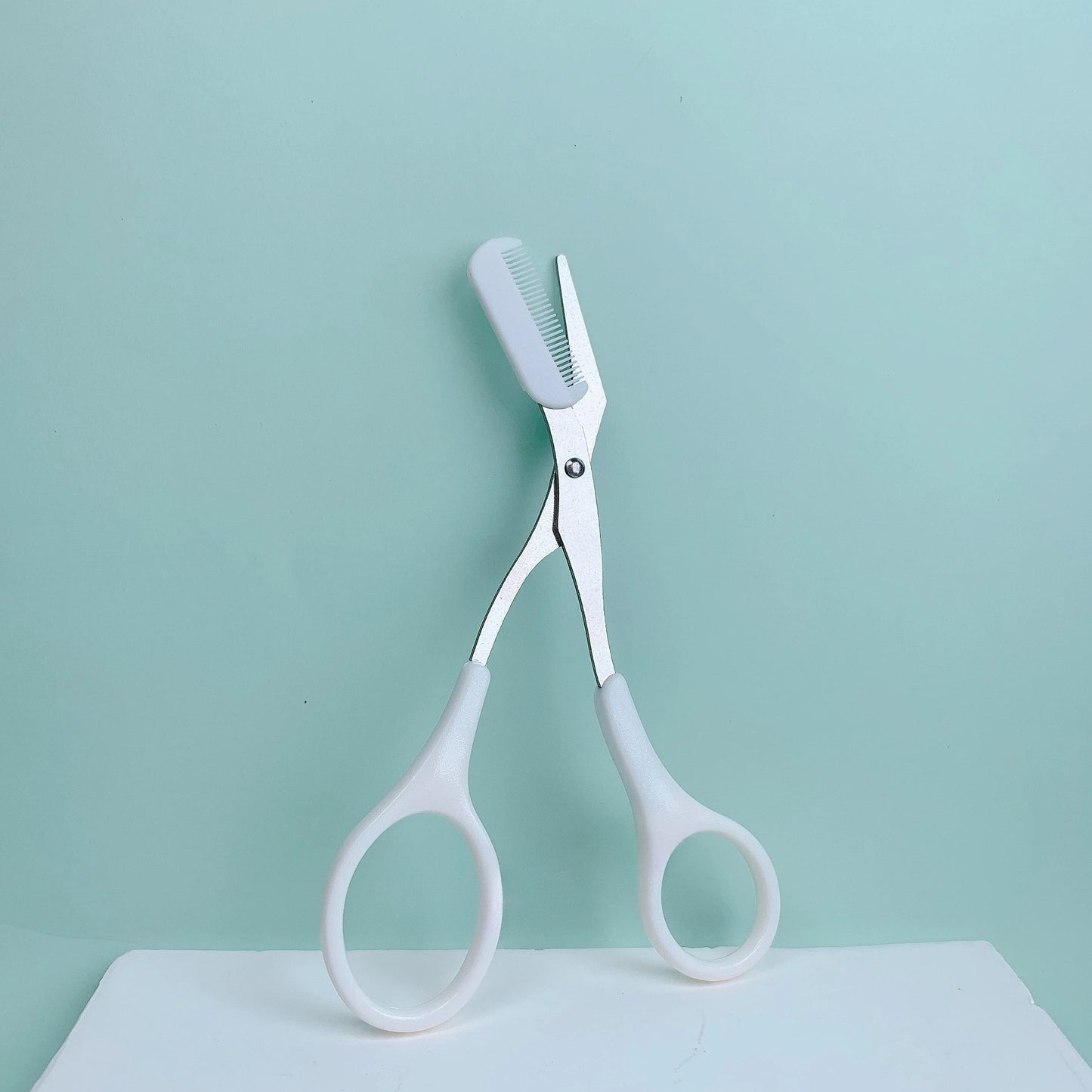 Pink eyebrow trimming scissors with built-in comb from Prime Deal Zone, stainless steel grooming tool for precise eyebrow shaping.