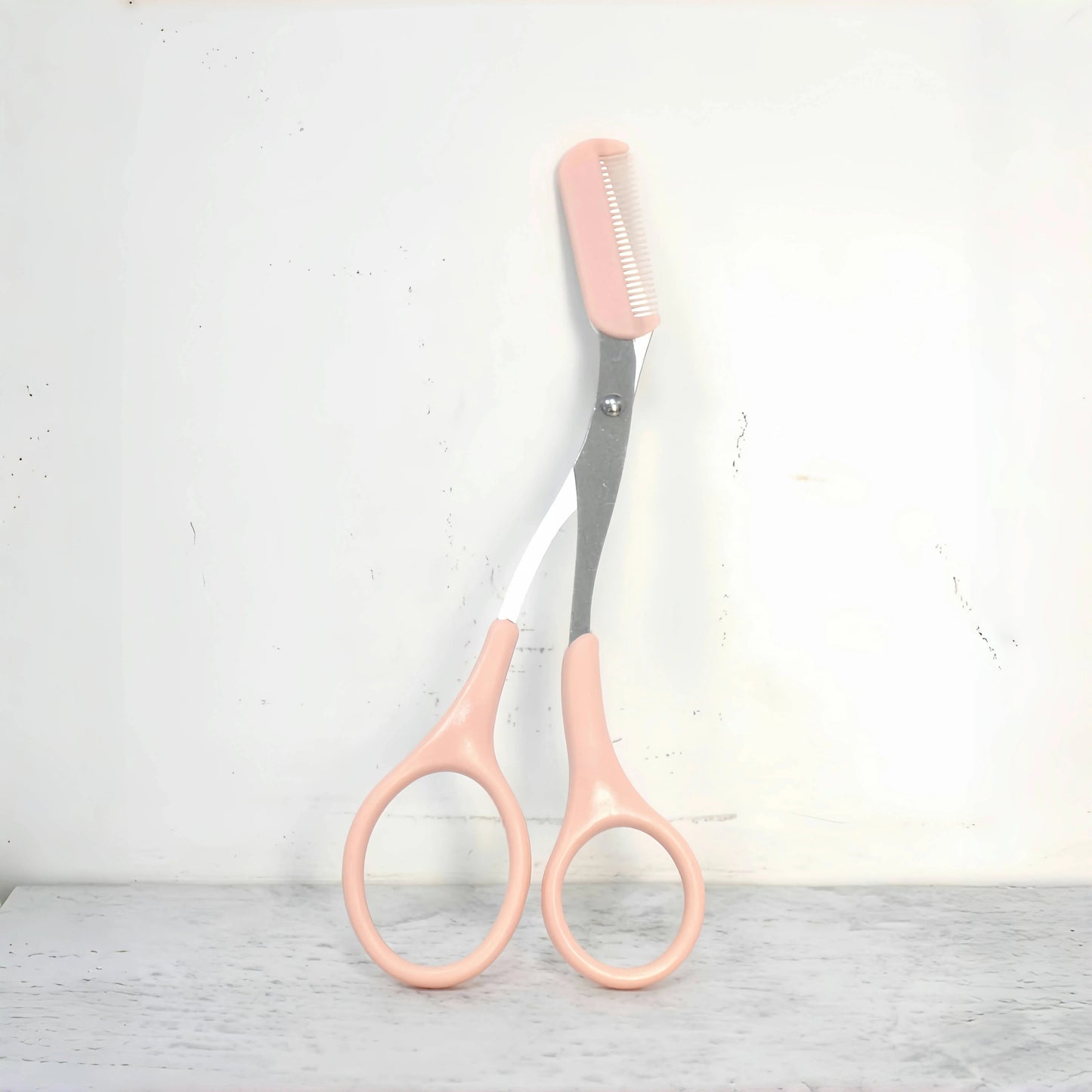 Pink stainless steel eyebrow trimming scissors with built-in comb from Prime Deal Zone for precise eyebrow grooming.